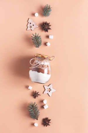 Homemade edible Christmas gift in a glass jar for making a chocolate drink on a beige backgroundの写真素材