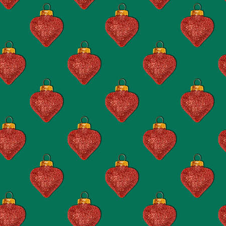 Seamless Christmas pattern with decorative shiny toys in the shape of a heart on a green backgroundの写真素材
