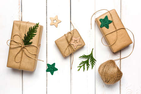 Christmas background with craft paper gift boxes and star decorations on a white wooden table.の写真素材