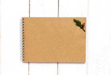 Christmas background with an empty craft paper notebook on a white wooden table. Mock up.の写真素材