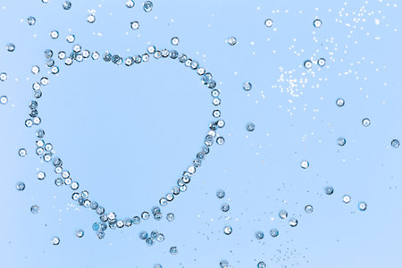 Heart-shaped frame made of silver sequins on a blue background. Festive textureの写真素材