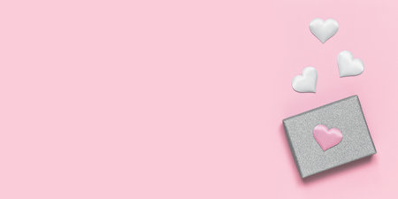 Silver gift box with decorative hearts on a pink background. Gift for Valentine's Day, Birthday, Mother's Day or International Women's Day. Bannerの写真素材