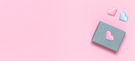 Silver gift box with decorative hearts on a pink background. Gift for Valentine's Day, Birthday, Mother's Day or International Women's Day. Bannerの写真素材