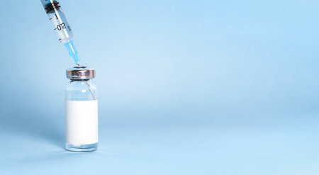 A bottle with a vaccine and a syringe in close-up. Concept of a vaccine against flu, measles. Bannerの写真素材