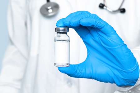 vaccine in a glass bottle in the hand of a doctor in a blue glove.の写真素材