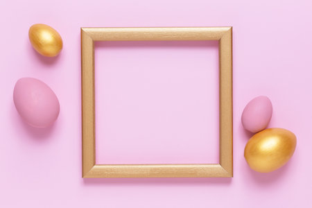 Golden and pink Easter eggs on pink pastel background, gold frame with space for text, flat lay image composition, top view. Easter decoration, modern design template.の写真素材