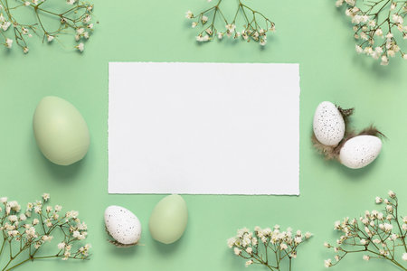 White and green Easter eggs, spring flowers on a green background. Flat lay, copy space. Easter decoration, modern design template.の写真素材