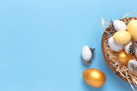 Easter background with colorful eggs in a basket on a blue background. Top view with copy spaceの写真素材