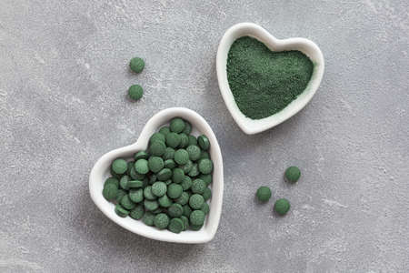 Green algae in powder and pills - chlorella, spirulina a gray background. Healthy green food supplement conceptの写真素材