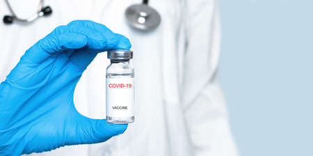 vaccine in a glass bottle in the hand of a doctor in a blue glove. The concept of a virus vaccineの写真素材