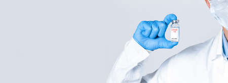 vaccine in a glass bottle in the hand of a doctor in a blue glove. The concept of a vaccineの写真素材