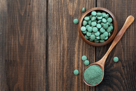 Green algae in powder and pills - chlorella, spirulina on a wooden background. Healthy green food supplement conceptの写真素材