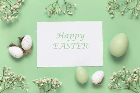 White and green Easter eggs, spring flowers on a green background. Flat lay, copy space.の写真素材