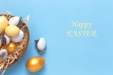 Easter background with colorful eggs in a basket on a blue background. Top view with copy space.の写真素材