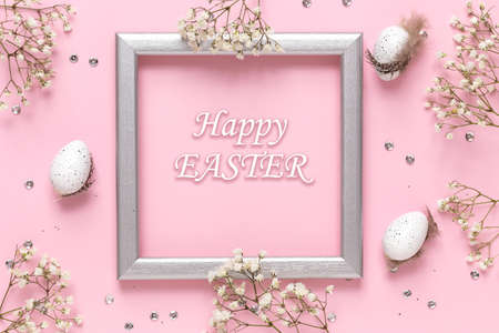 Easter eggs and spring flowers on a pink pastel background, silver frame with space for text, flat image composition.の写真素材