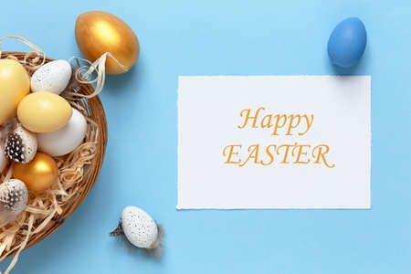 Easter background with colorful eggs in a basket on a blue background. Top view with copy space, mock up.の写真素材