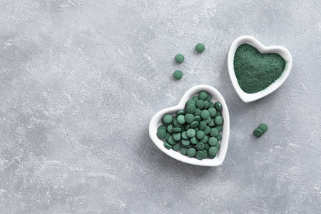 Green algae in powder and pills - chlorella, spirulina a gray background. Healthy green food supplement conceptの写真素材