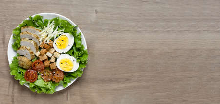Caesar salad with fried chicken, fresh tomatoes, croutons, lettuce, parmesan cheese and eggs. Healthy eating. Bannerの写真素材