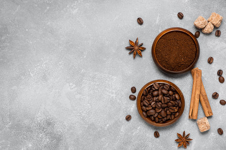 Coffee beans, ground coffee, brown sugar cane, star anise and cinnamon in wooden bowls on a gray backgroundの写真素材