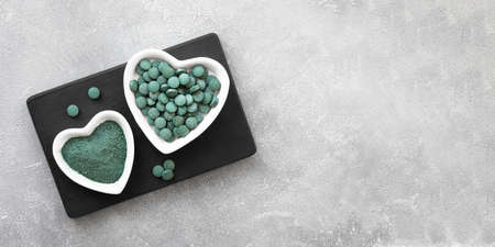 Green algae in powder and pills - chlorella, spirulina a gray background. Healthy green food supplement conceptの写真素材