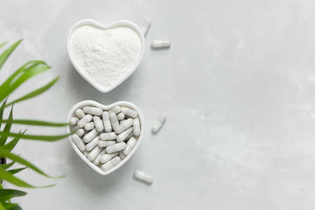Collagen powder and pills on a gray background with a copy space. Natural beauty and health supplement.の写真素材