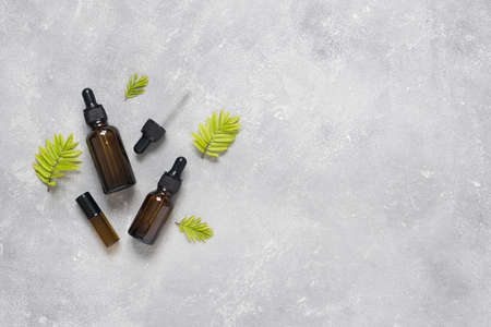 Bottles of dark amber glass with essential oil and face cream on a gray concrete background. Natural SPA organic cosmetic. Layout of the beauty salon branding. Flat lay, top view.の写真素材