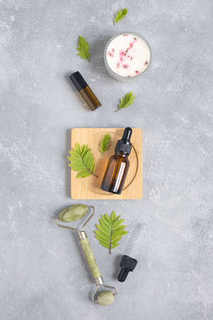 Containers of lotion, essential oils, massage rollers on a gray concrete background. Natural organic eco cosmetics. Layout of the beauty salon branding. Flat lay, top viewの写真素材
