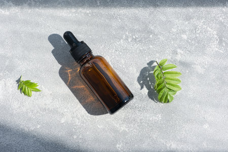 A glass bottle with a pipette for oil, lotion or serum on a gray concrete background. Natural SPA cosmetic products background. Layout of the beauty salon brandingの写真素材