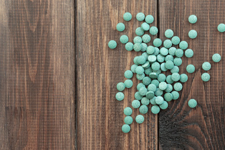 Green algae pills - chlorella, spirulina on a wooden background. Healthy green food supplement concept.の写真素材