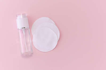 Reusable glass white bottle for oil, cream, lotion or serum and reusable cotton pads on a pink background. Zero waste, reusable, eco friendly makeup remover and washing conceptの写真素材