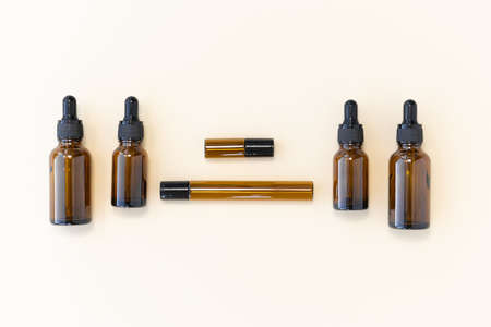 Bottles of dark amber glass with essential oil and face cream on a beige background. Natural SPA organic cosmetic. Layout of the beauty salon branding. Flat lay, top view.の写真素材