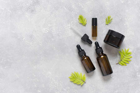 Bottles of dark amber glass with essential oil and face cream on a gray concrete background. SPA organic cosmetic.の写真素材