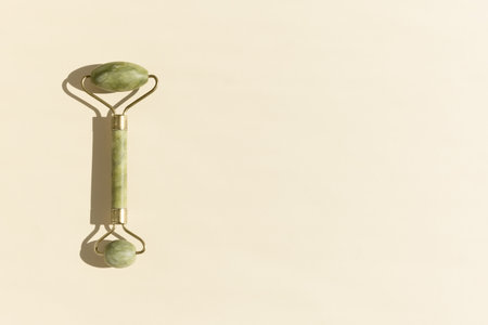Jade Green Facial Massage Roller on a beige background. Skin Care Concept.の写真素材