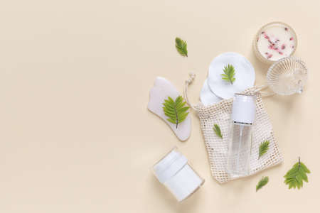 Reusable glass white bottles for oil, cream, lotion or serum, reusable cotton pads and a gouache scraper on a beige background. Zero waste, reusable, eco friendly makeup remover and washing conceptの写真素材