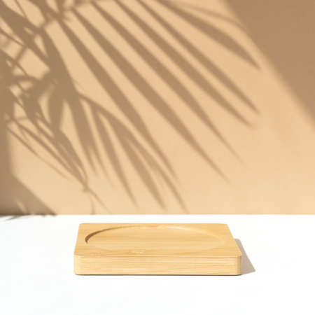 Minimal abstract background for the presentation of a cosmetic product. Wooden scene on a white table. Premium podium with a shadow of tropical palm leaves on a pink wall. Showcase, display case.の写真素材