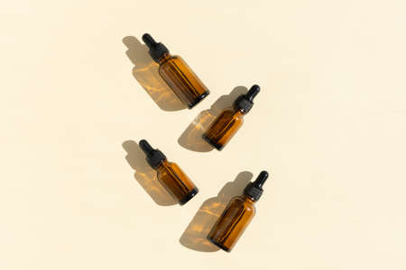Bottles of dark amber glass with essential, lotion, serum on a beige background. Natural SPA organic...