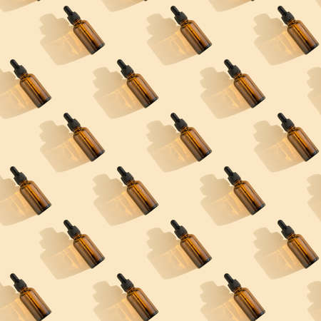 Seamless pattern. Bottles of dark amber glass with essential, lotion, serum on a beige background. Natural SPA organic cosmetic. Layout of the beauty salon branding. Flat layの写真素材