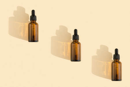 Bottles of dark amber glass with essential, lotion, serum on a beige background. Natural SPA organic cosmetic. Layout of the beauty salon branding. Flat lay, top view.の写真素材