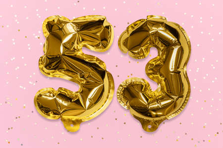 The number of the balloon made of golden foil, the number fifty-three on a pink background with sequins. Birthday greeting card with inscription 53. Numerical digit, Celebration event, template.の写真素材