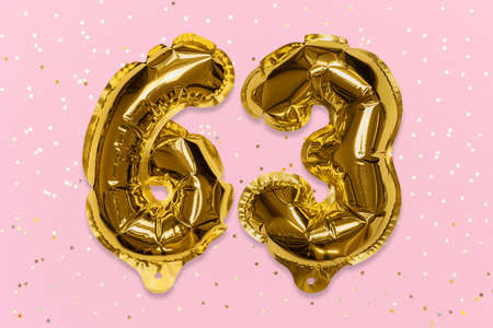 The number of the balloon made of golden foil, the number sixty-three on a pink background with sequins. Birthday greeting card with inscription 63. Numerical digit, Celebration event, template.の写真素材