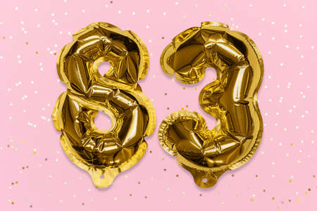 The number of the balloon made of golden foil, the number eighty-three on a pink background with sequins. Birthday greeting card with inscription 83. Numerical digit, Celebration event, template.の写真素材