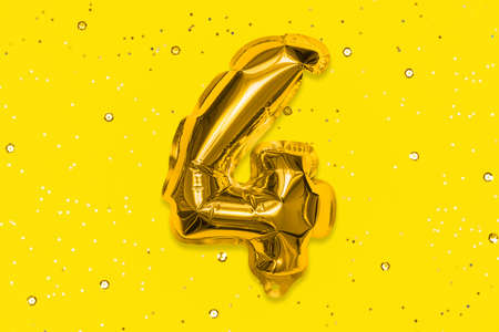 The number of the balloon made of golden foil, the number four on a yellow background with sequins....