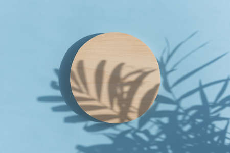 Abstract minimal scene of a geometrical form. A cylindrical wooden podium on a pastel blue...