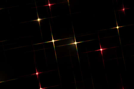 Multicolored lights garlands in the shape of stars on a black background. Blurry festive sparkling...