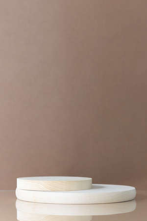 Cylindrical wooden scenes on a beige table on a brown background. Premium podium for advertising your product. Background for the product presentation.の写真素材