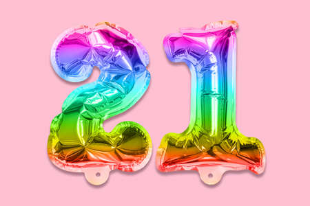 Rainbow foil balloon number, digit twenty one on a pink background. Birthday greeting card with inscription 21. Top view. Numerical digit. Celebration event template.の写真素材