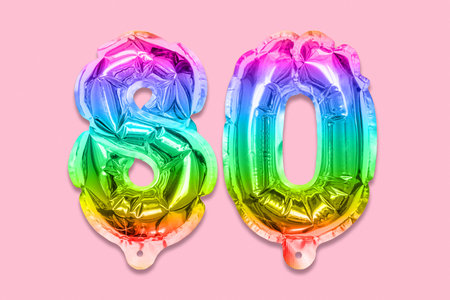 Rainbow foil balloon number, digit eighty on a pink background. Birthday greeting card with inscription 80. Anniversary concept. top view. Numerical digit. Celebration event template.の写真素材