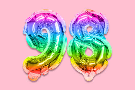 Rainbow foil balloon number, digit ninety eight on a pink background. Birthday greeting card with inscription 98. Top view. Numerical digit. Celebration event template.の写真素材