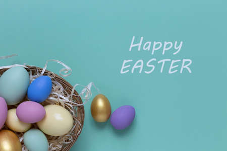 Easter background with colorful eggs in a basket on a blue background. Top view with copy space.の写真素材