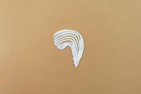 White cream texture on a beige background. Smear of skincare cosmetics product. wellness and beauty concept.の写真素材